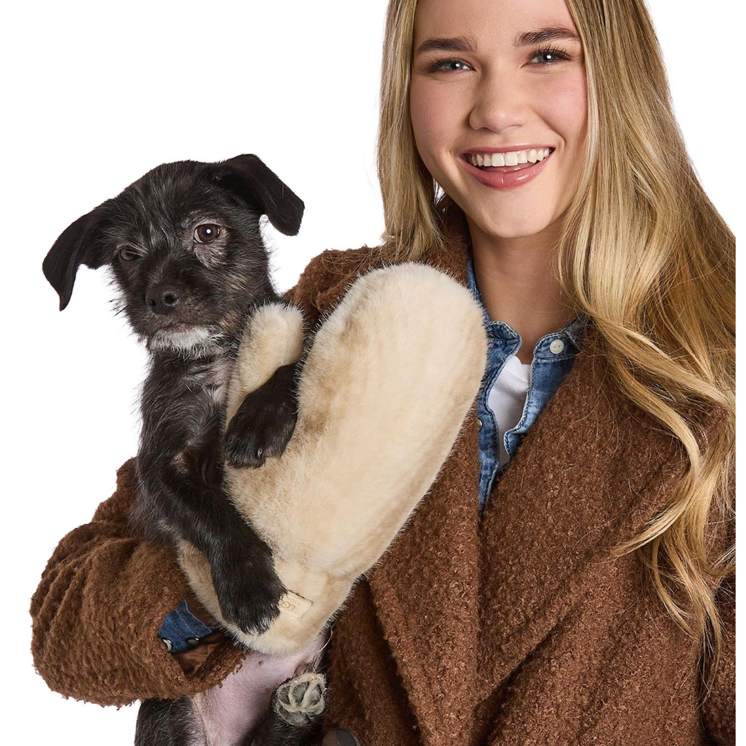Woman holding a small black dog in a brown coat with a white background