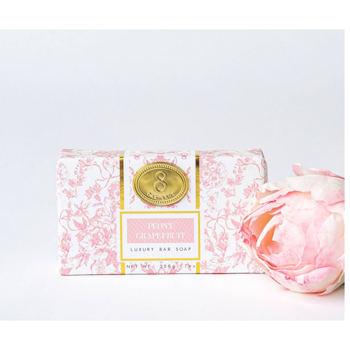 Luxury bar soap with decorative packaging and a pink rose on a light gray background