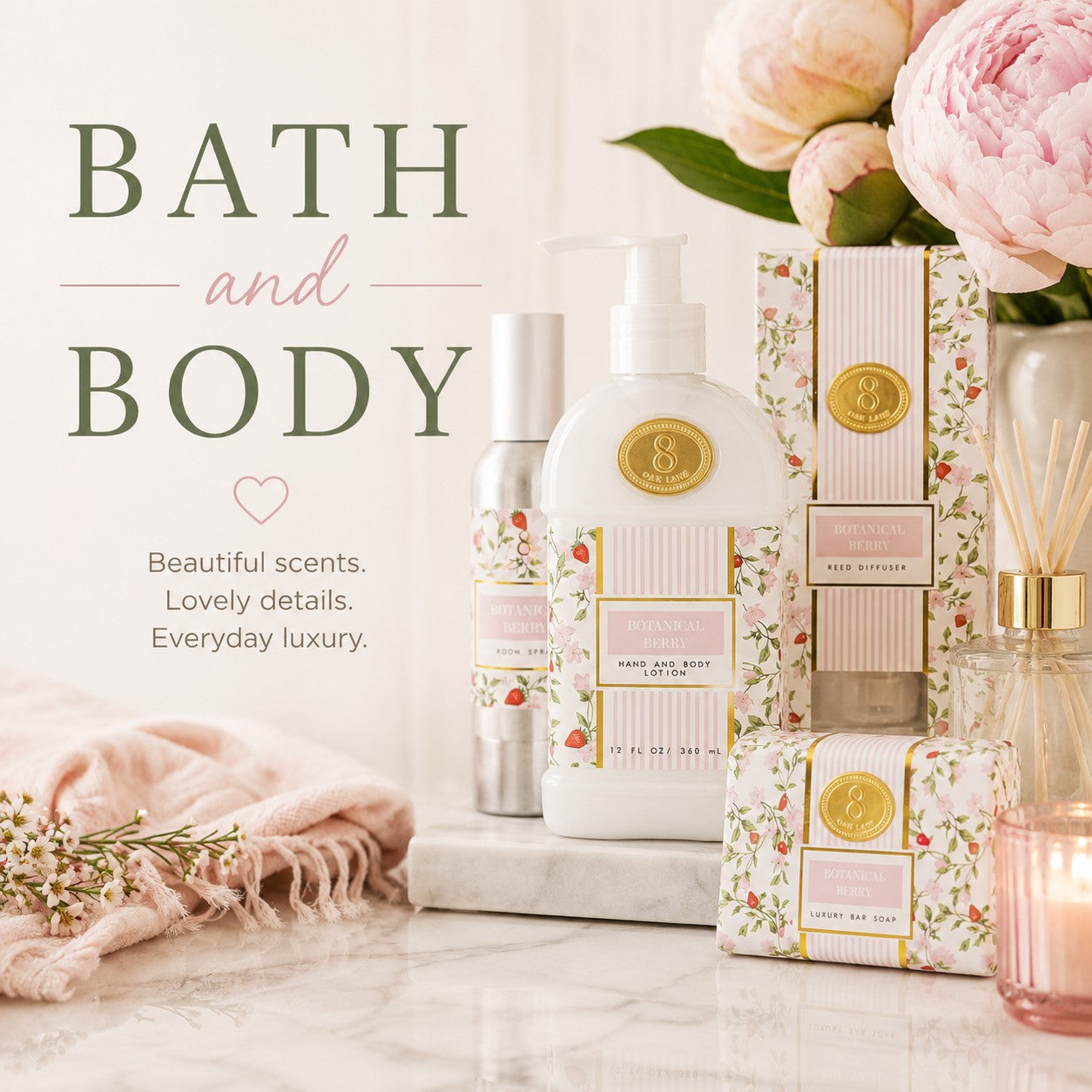 A styled bath and body product set on a marble surface with pink flowers, a folded pink towel, and a lit reed diffuser. Visible products include a white pump bottle labeled 'Rose & Sage Body Lotion', a silver bottle, floral-patterned boxes and wrapped items, and a pink glass reed diffuser bottle with gold accents.