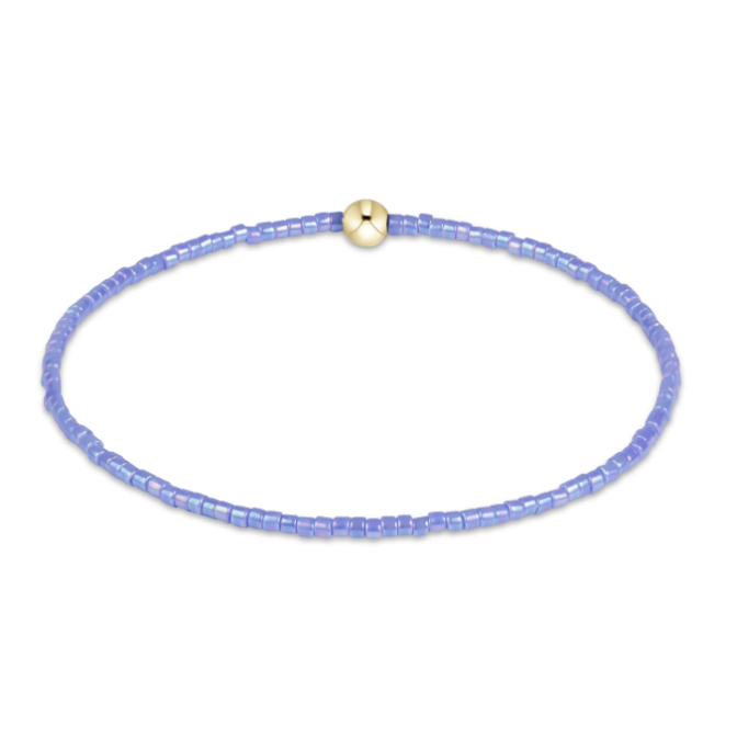 A beaded bracelet made of small lavender-blue translucent beads with a single round gold bead, shown on a plain white background.