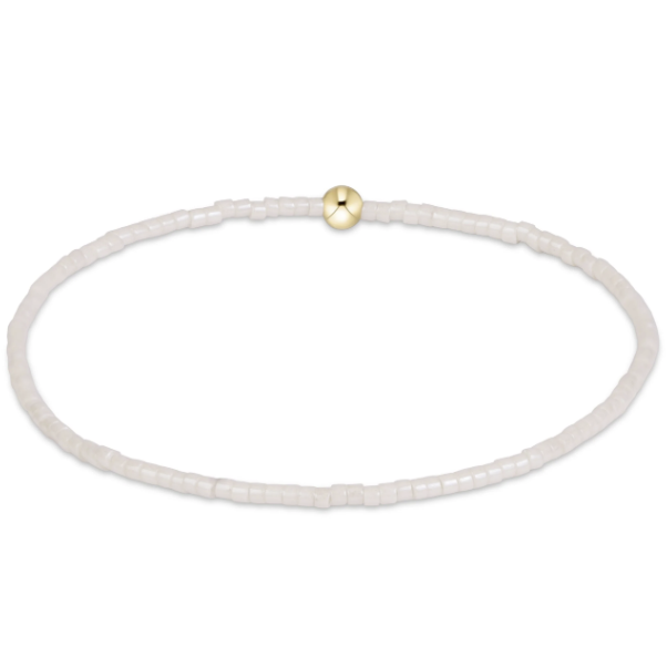 A delicate beaded bracelet made of small white cylindrical beads, featuring a single polished gold round bead at the top center, displayed on a clean white background.