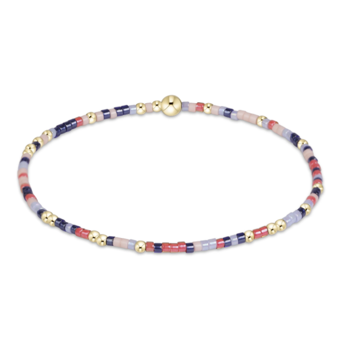 A delicate beaded bracelet with alternating segments of navy blue, dusty pink, and light lavender beads, accented by small gold spacers and a polished gold bead, shown on a solid white background.