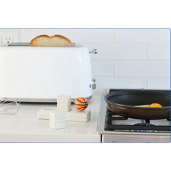 Kitchen counter with a toaster, pan, and sports ball on a white tiled wall background