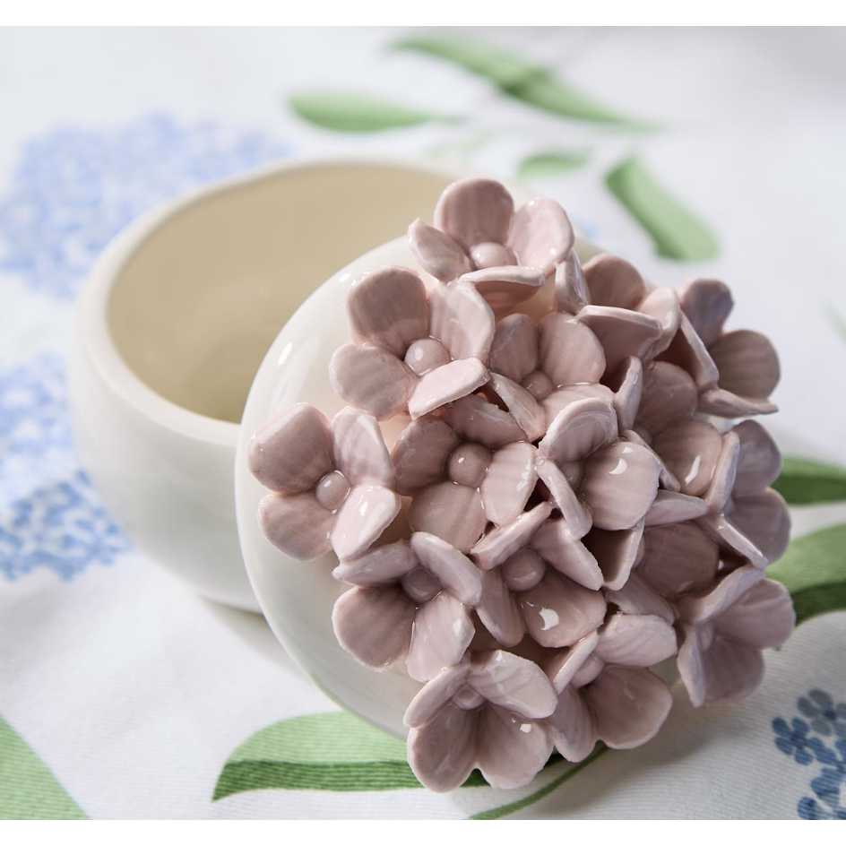 Pink ceramic flower on a white plate with a floral tablecloth in the background